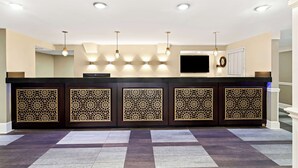 A reception area with a dark counter, decorative panels, recessed ceiling lights, and a flat-screen TV. - Best Western Riverside Inn (Macon)