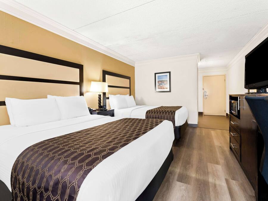 A hotel room with two beds, a TV, a desk, and a chair.