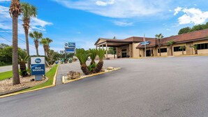 A Best Western hotel with a covered entrance, palm trees, and a clear blue sky. - Best Western Riverside Inn (Macon)