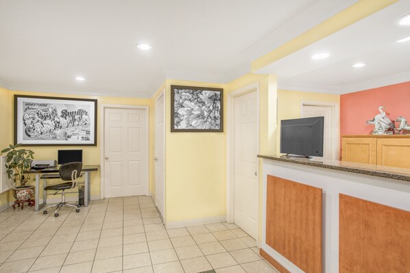 A reception area with a desk, computer, and framed artwork.