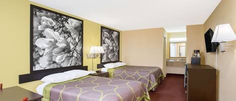 A hotel room with two beds, a desk, a chair, a dresser, a mirror, and a lamp.