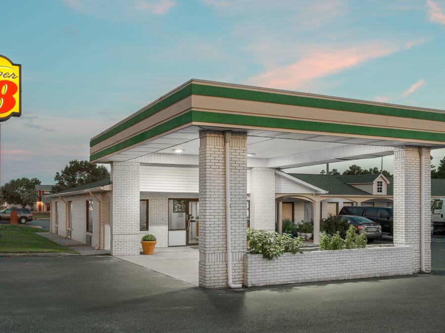 Et Super 8 motel med grønt tag, hvide mursten og parkeringsdæk.