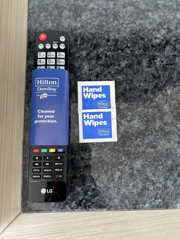 Un control remoto con la marca Hilton CleanStay y un paquete de toallitas húmedas.