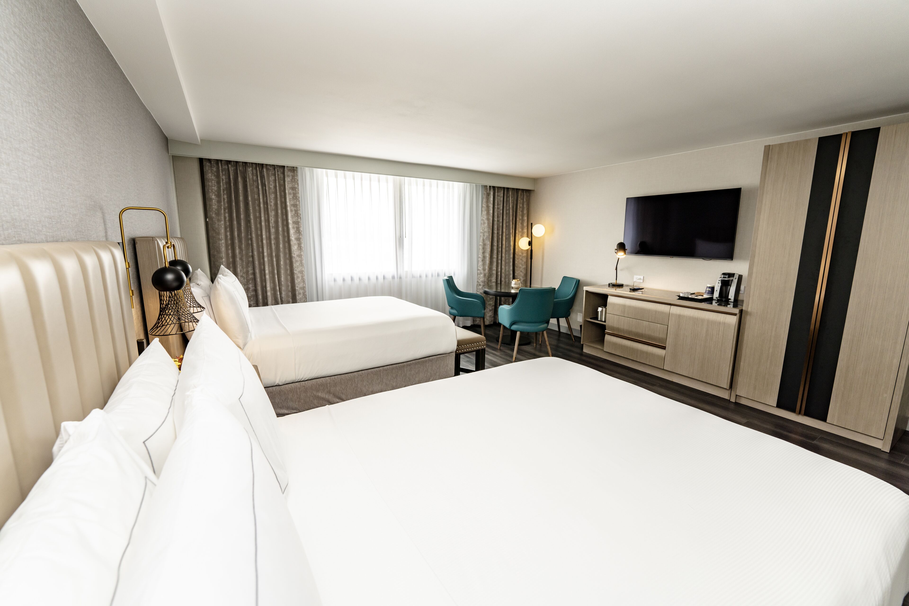Una habitación de hotel con dos camas, un escritorio, un televisor y un minibar.