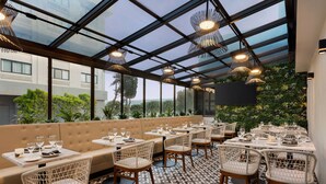Restaurante com teto de vidro, assentos acolchoados e piso estampado.
