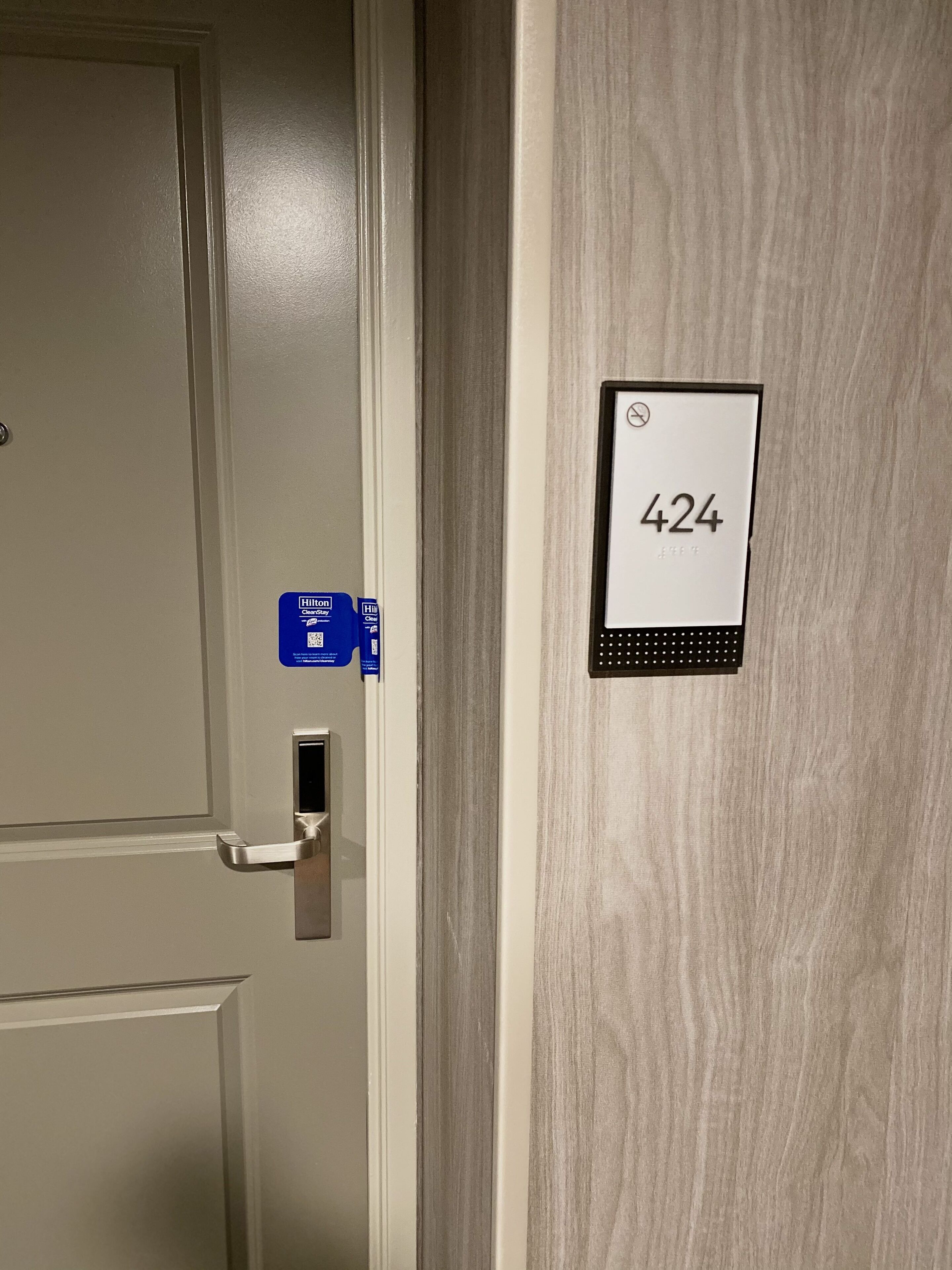 A hotel room door with a number sign '424' and a blue hotel card on the wall.
