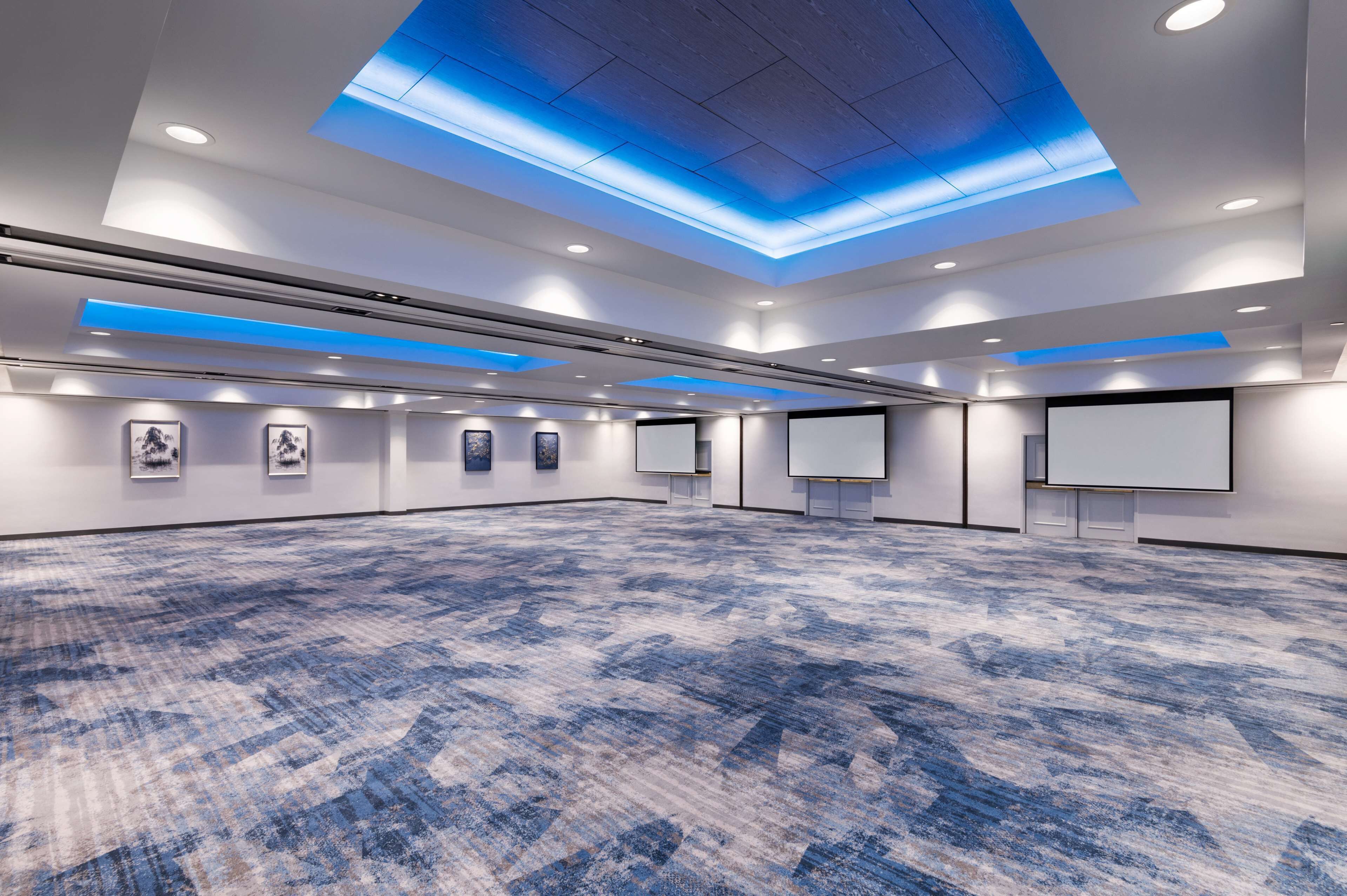 A spacious conference room with a patterned carpet, recessed lighting, and a skylight.