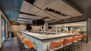 Uma cozinha moderna com uma ilha central, banquetas e uma grande janela.