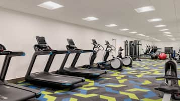 Un gimnasio con cintas de correr, pelotas de ejercicio y máquinas de pesas.