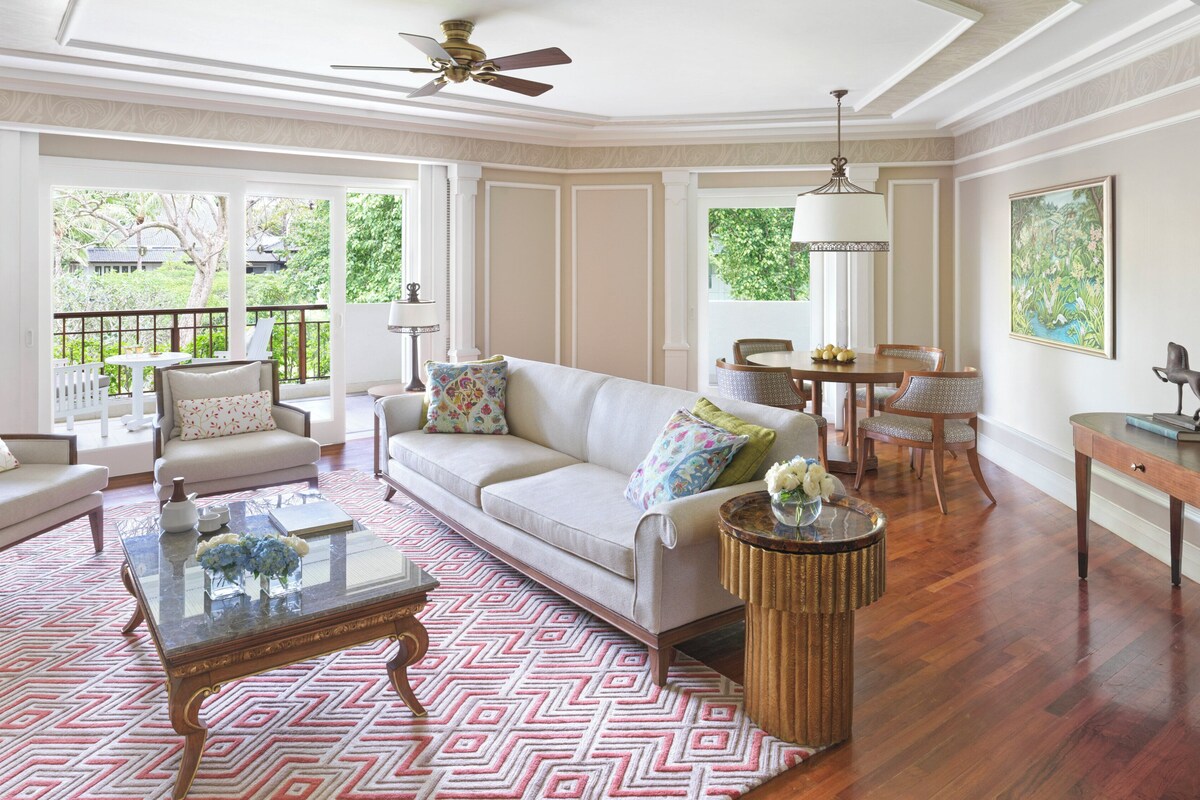 A spacious living room with a sofa, armchairs, a coffee table, and a dining area with a table and chairs.