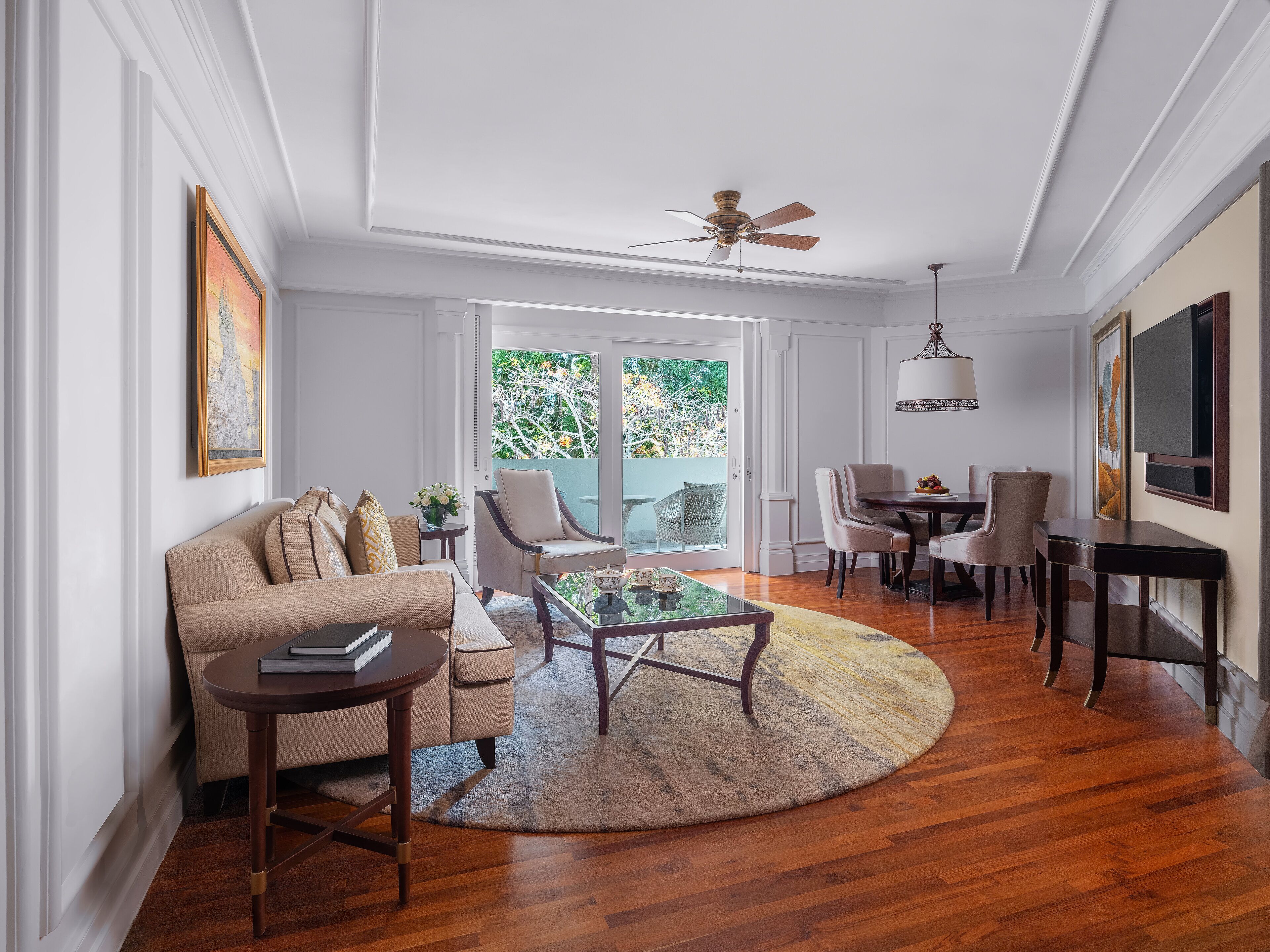 A spacious living room with a sofa, armchairs, a coffee table, and a dining area with chairs and a table.
