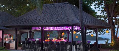 Un área de bar al aire libre con asientos y vista al agua.