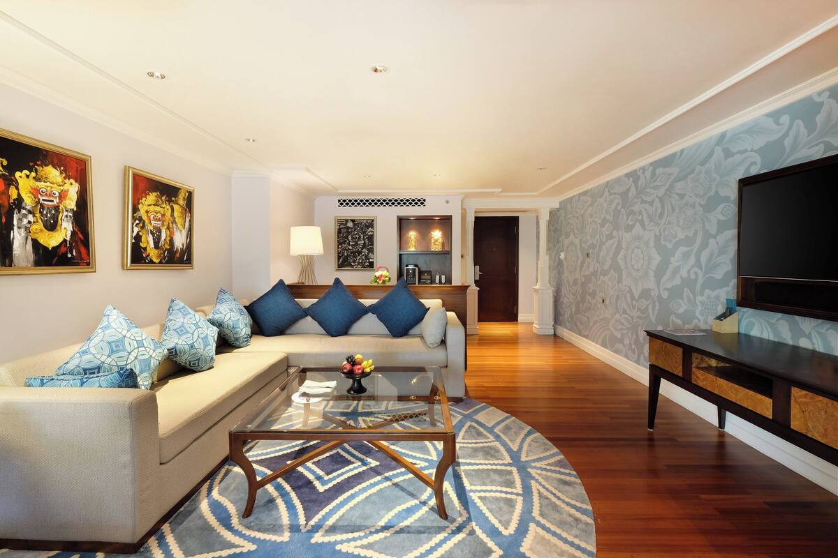 A modern living room with a sofa, coffee table, and a TV. There is a kitchen area in the background.