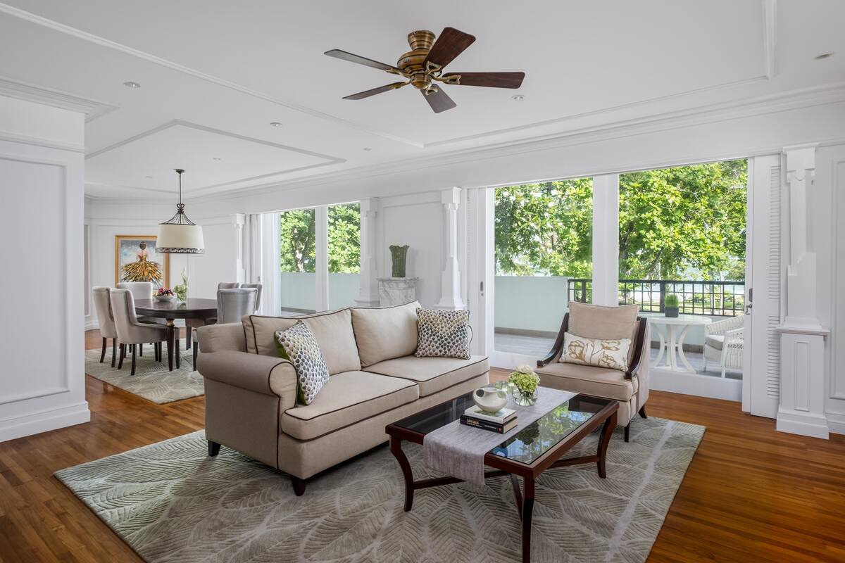A spacious living room with a beige sofa, a coffee table, and a ceiling fan.