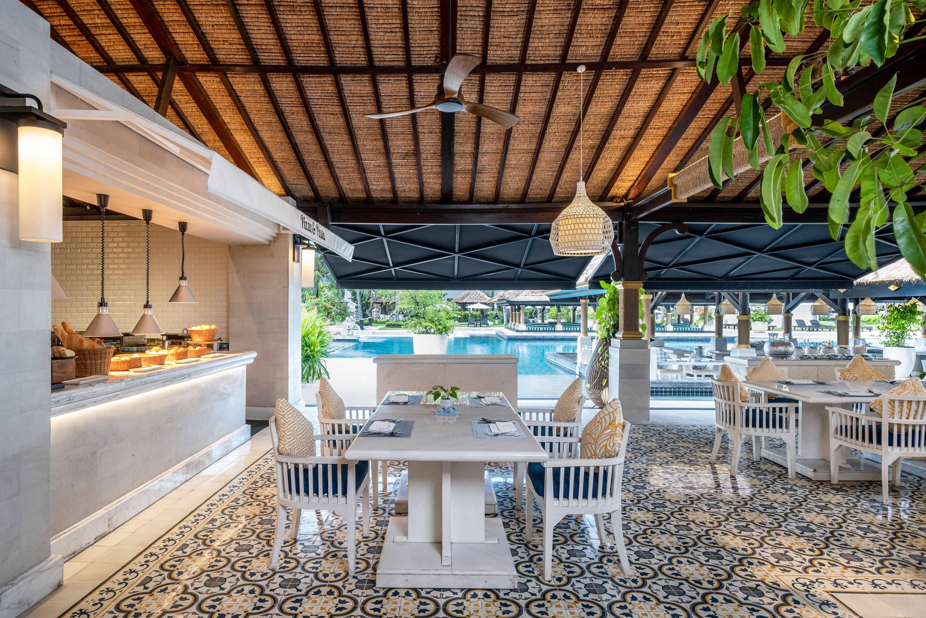 Un espacio de comedor al aire libre cubierto con una piscina al fondo.
