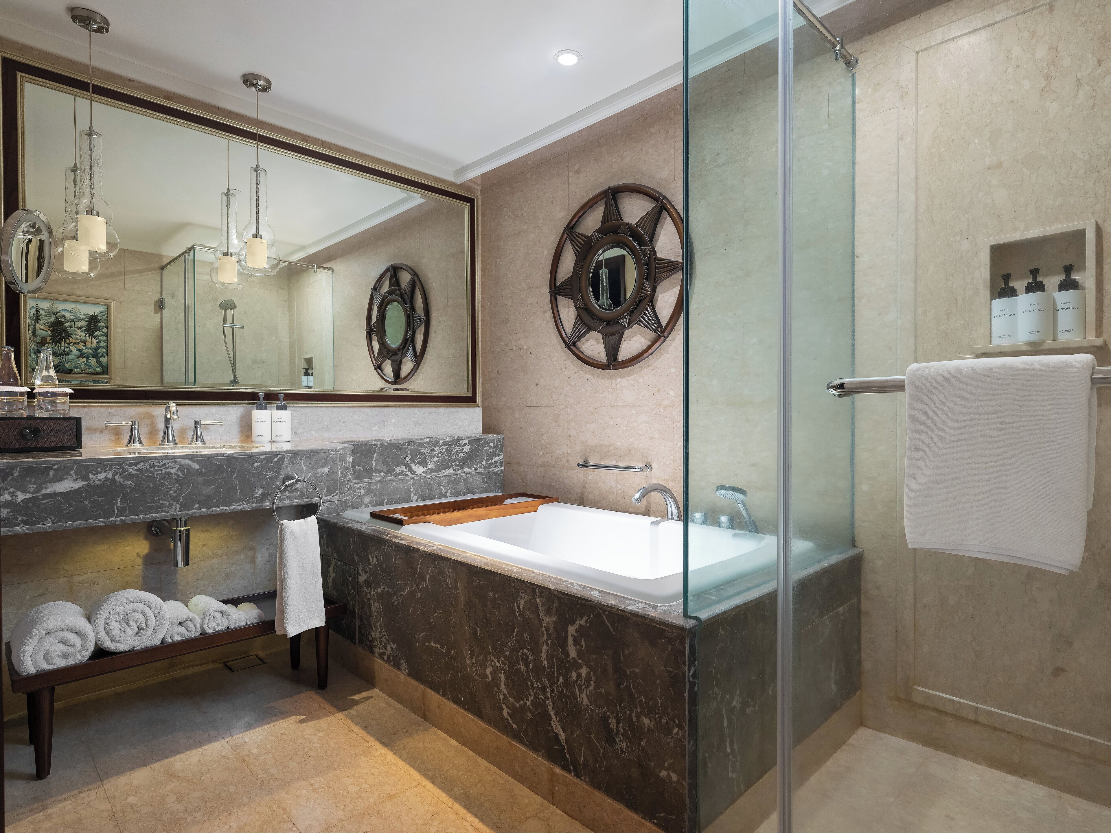 Une salle de bain moderne avec un lavabo en marbre, un grand miroir, une baignoire et une douche à parois de verre.
