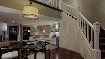 A spacious living area with a dining table, chairs, and a staircase leading to an upper floor.