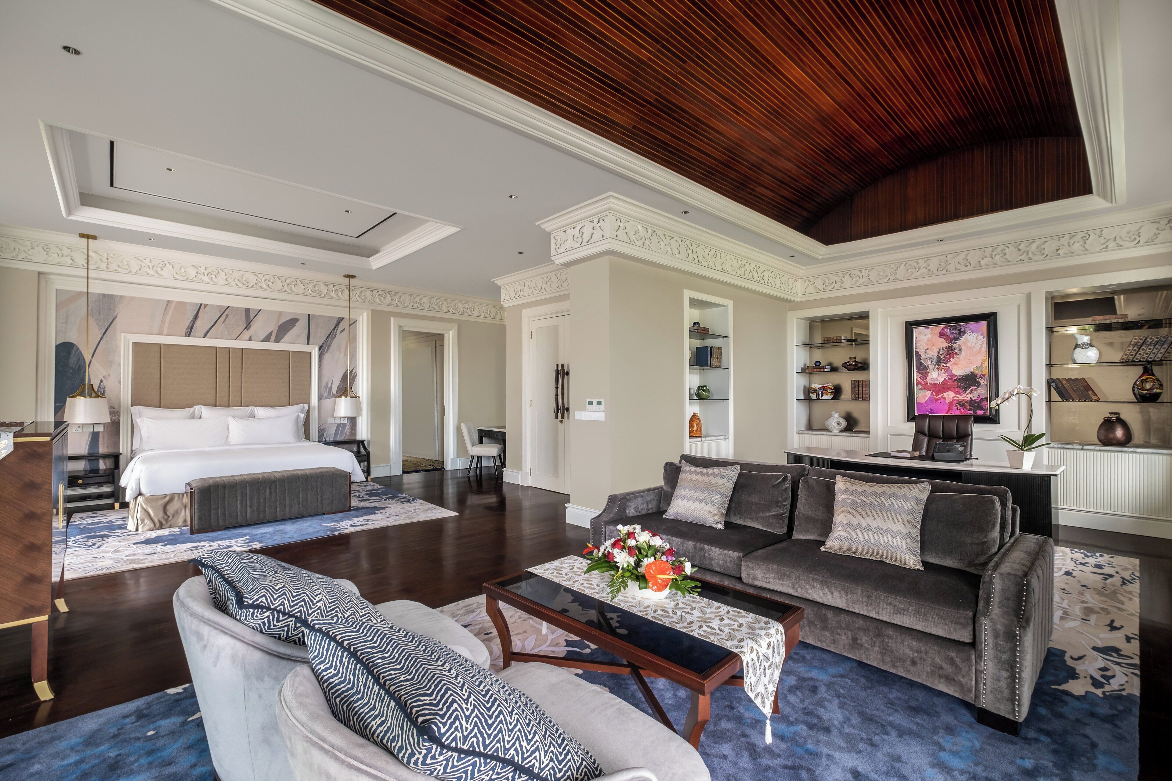 A spacious hotel room with a large bed, a sofa, a coffee table, and a dining area.