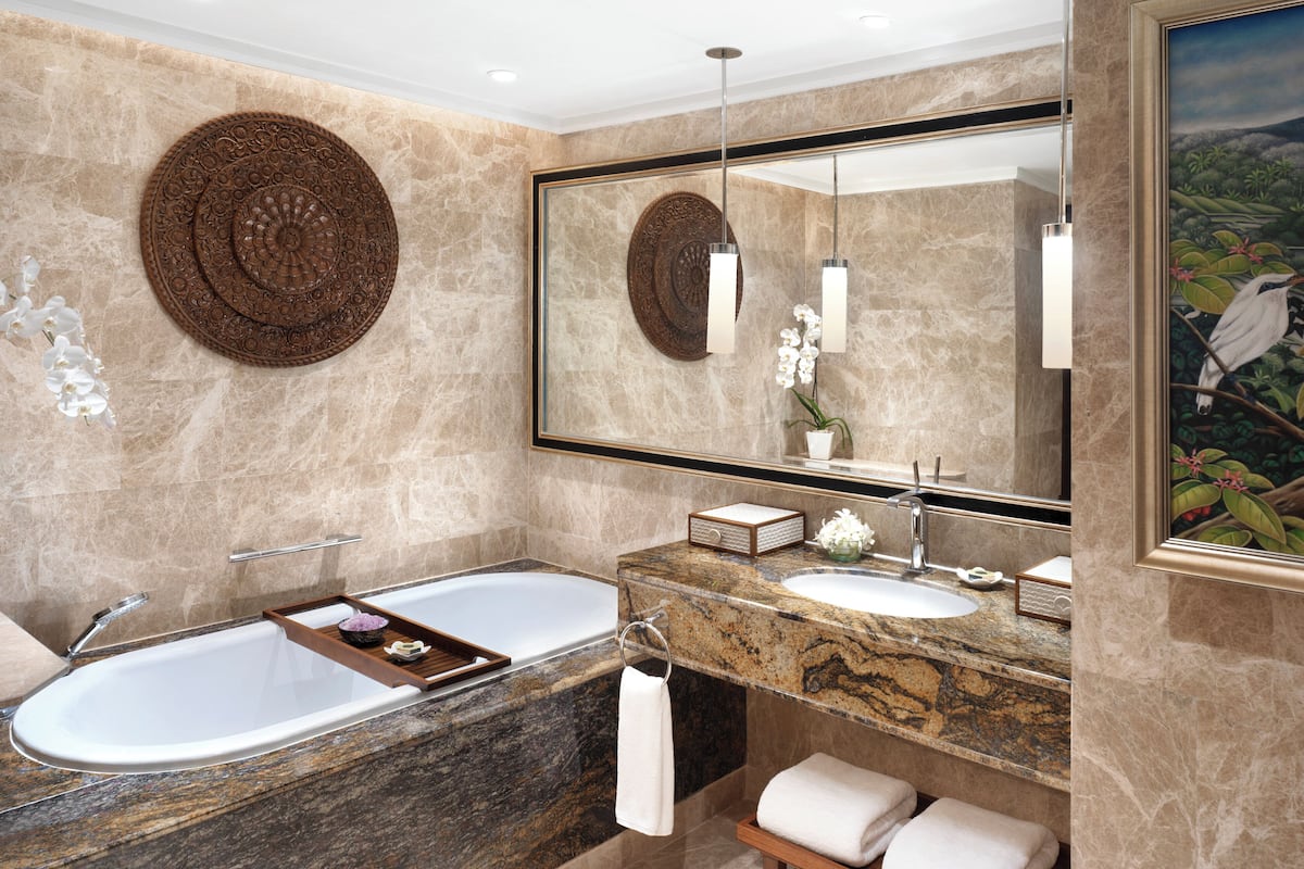 A modern bathroom with a bathtub, a large mirror, and a marble countertop.