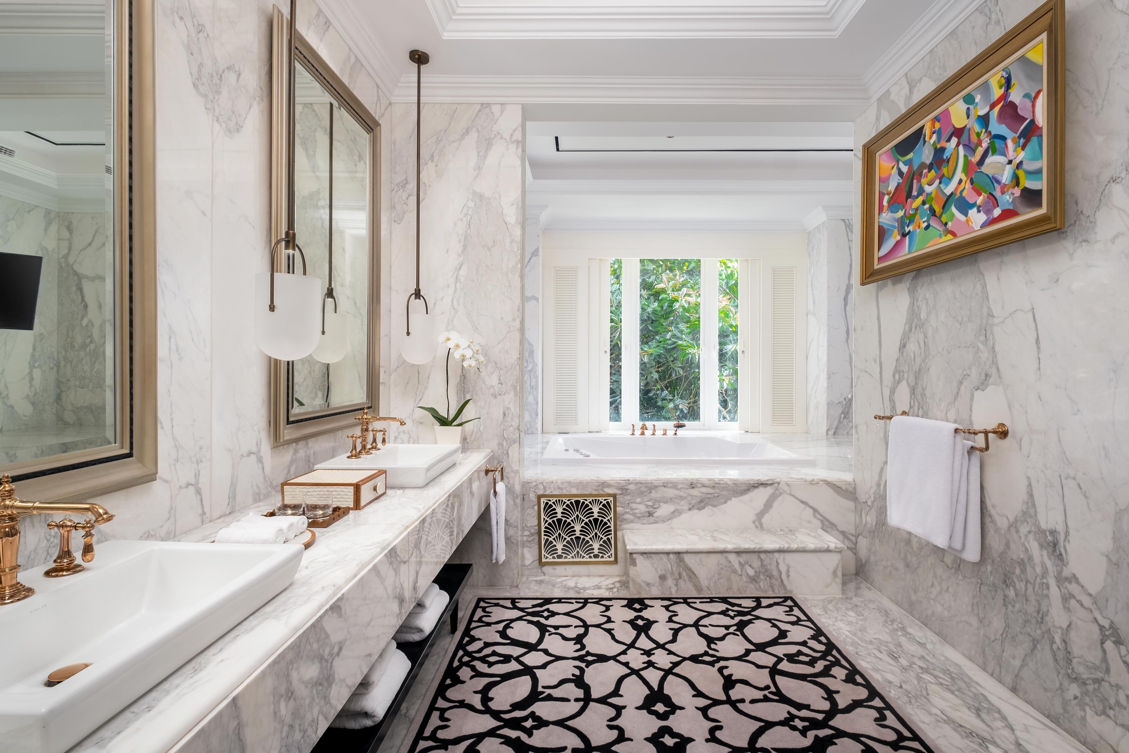 A luxurious bathroom with marble walls, a large bathtub, and a modern vanity.