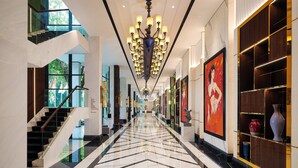 A modern hotel lobby with a geometric marble floor, a grand chandelier, and a staircase leading to an upper level. - InterContinental Bali Resort by IHG (Jimbaran)