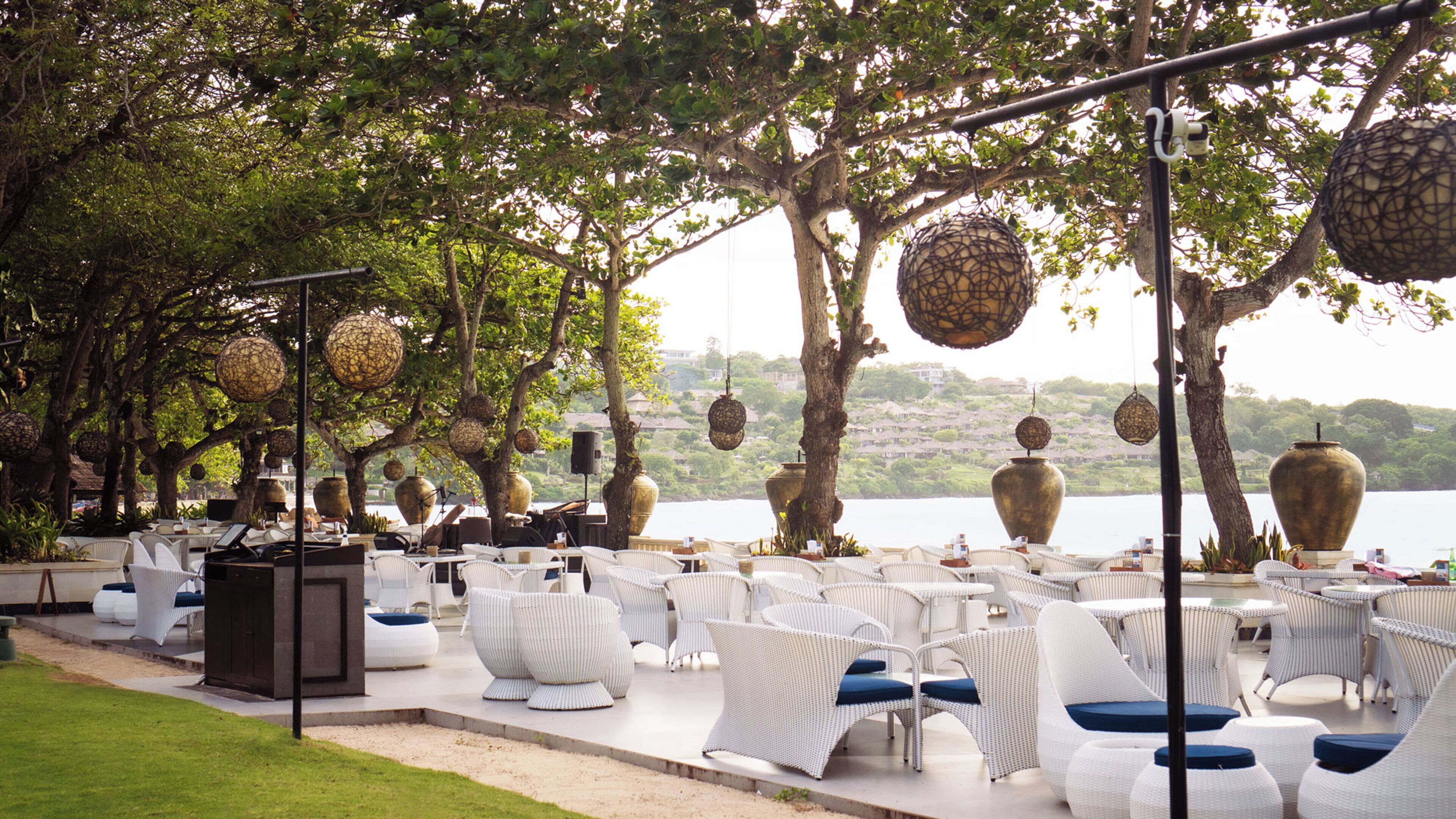 An outdoor seating area with wicker furniture, large decorative vases, and hanging spherical ornaments.