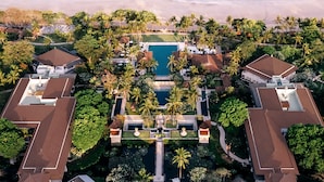 An aerial view of a resort with a central swimming pool, multiple guest villas, and a beach. - InterContinental Bali Resort by IHG (Jimbaran)