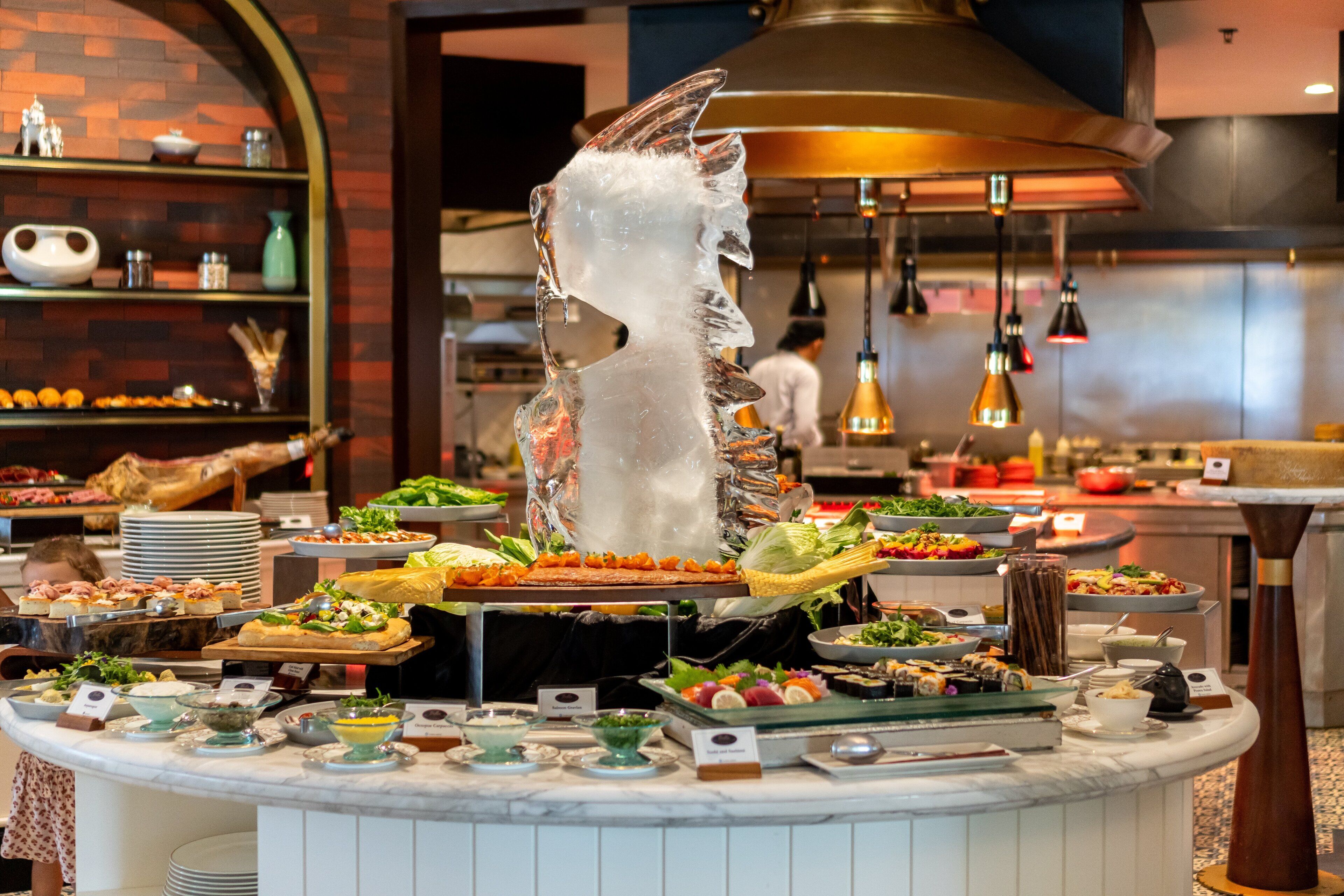A buffet with various dishes and a decorative ice sculpture.