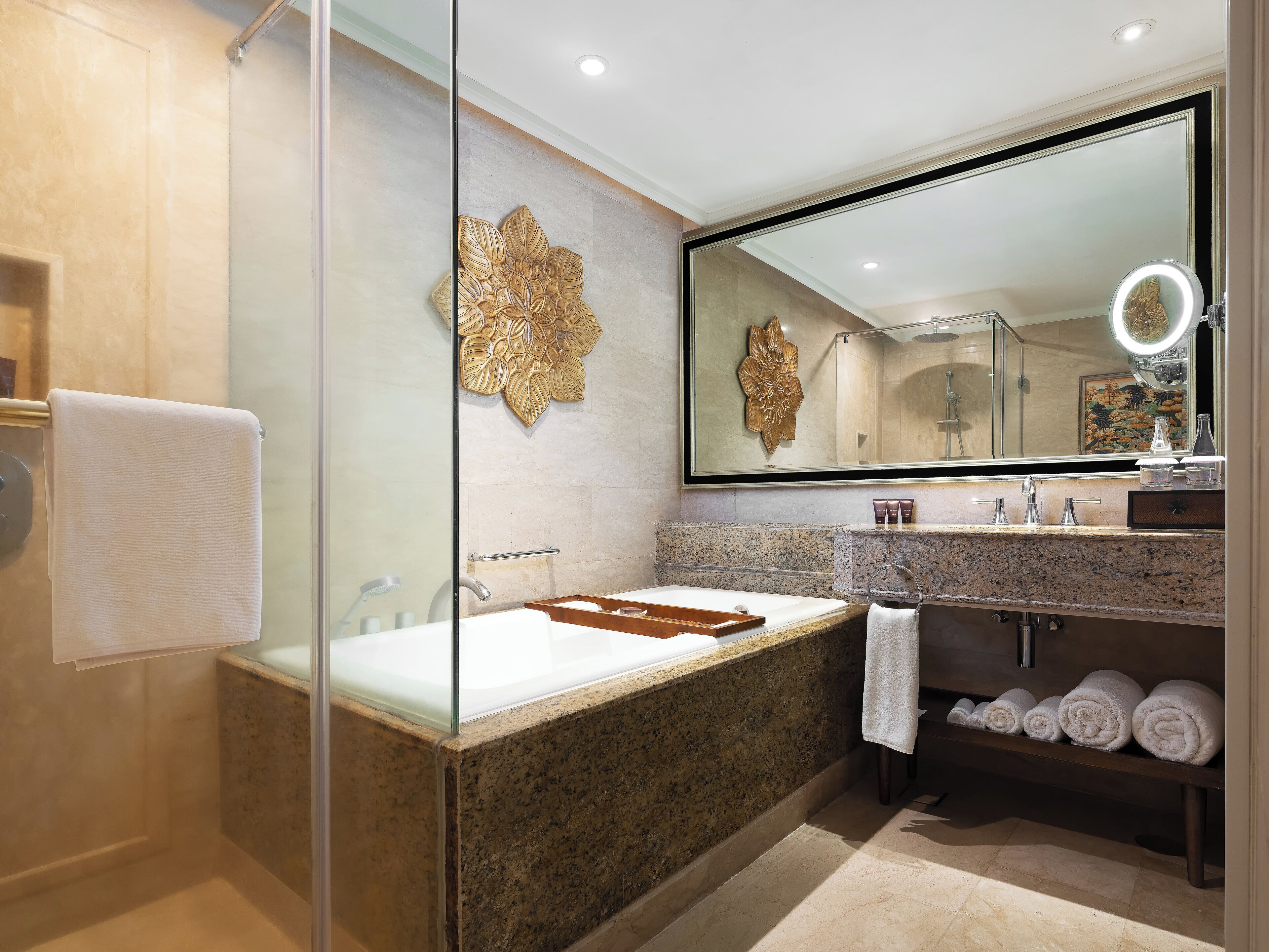 Un bagno moderno con box doccia in vetro, uno specchio grande e un piano lavabo in marmo.