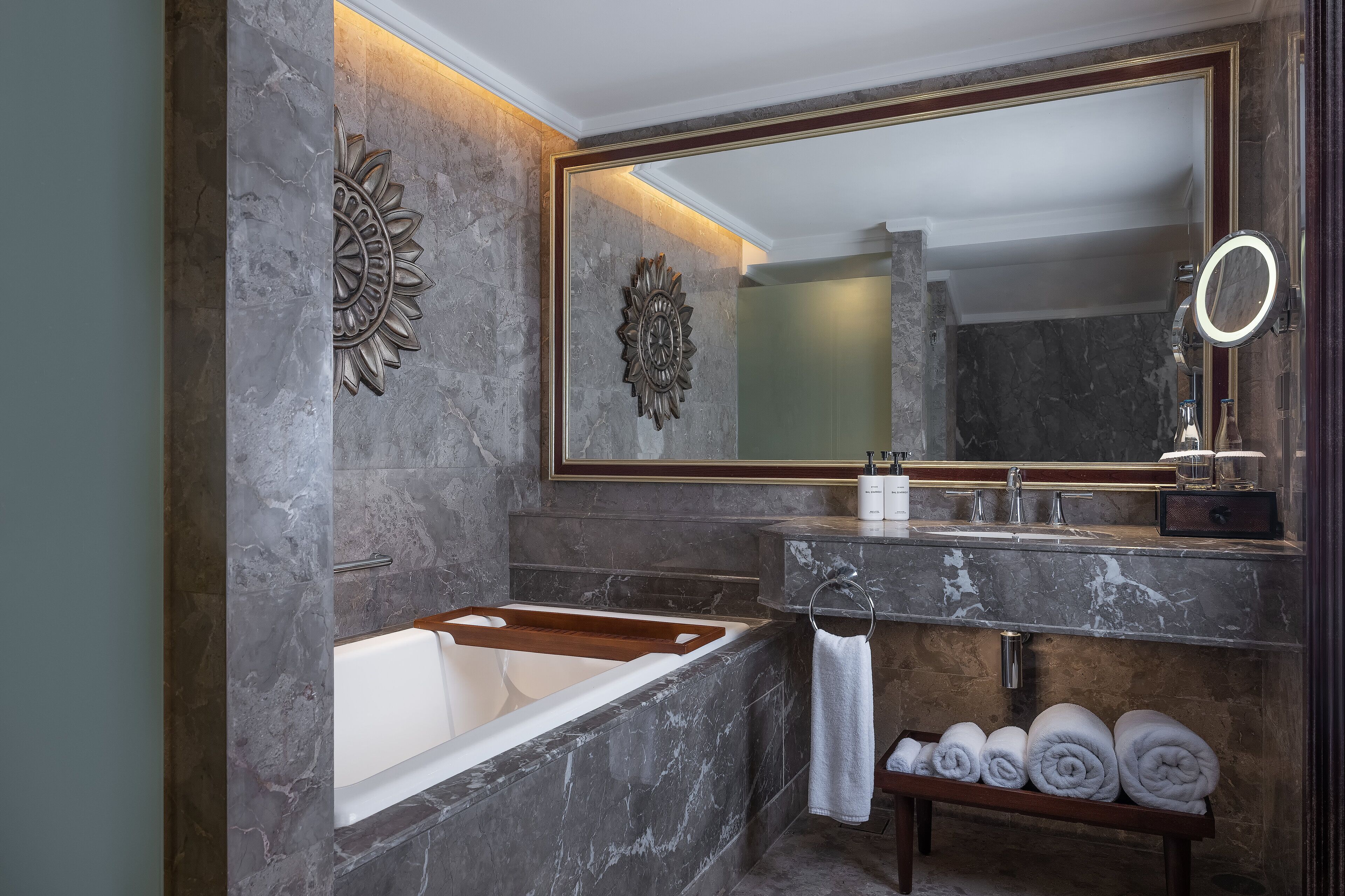 A modern bathroom with a marble sink, a large mirror, and a bathtub.