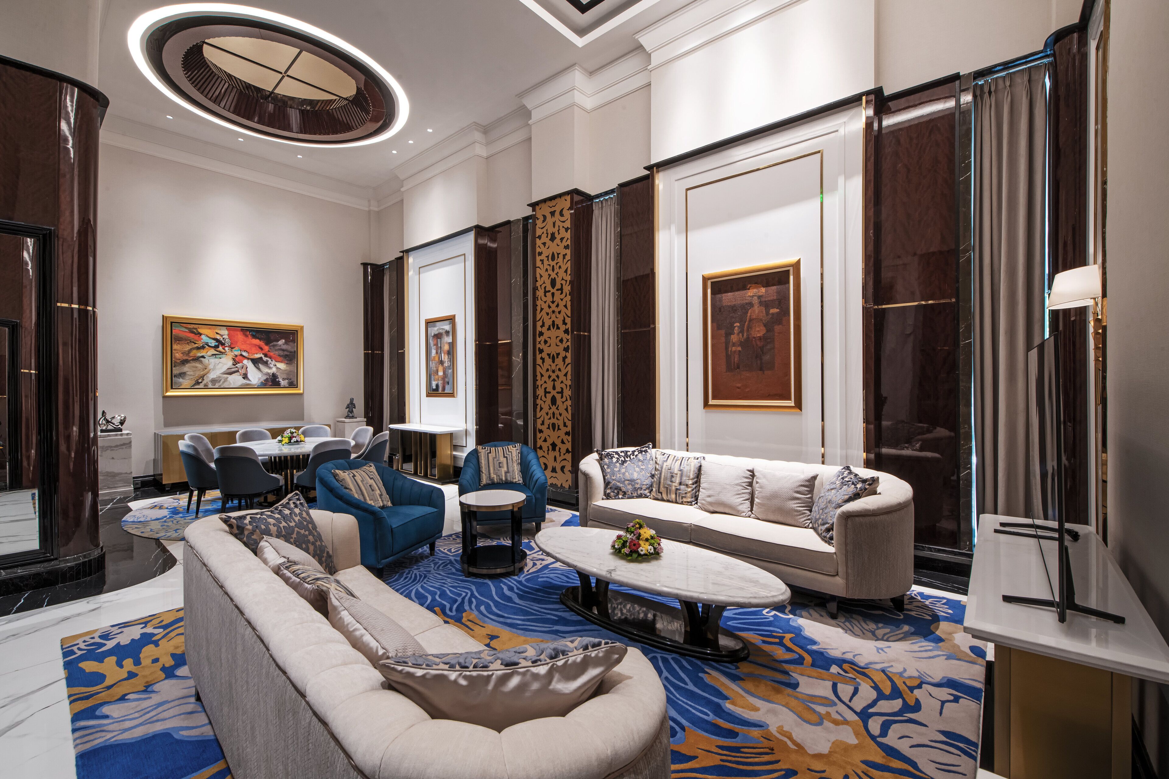 A spacious living room with a large sofa, a coffee table, and a dining area with chairs and a table.