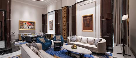 A spacious living room with a large sofa, a coffee table, and a dining area with chairs and a table.