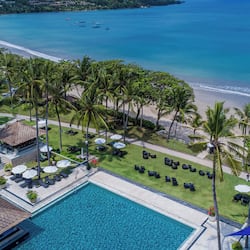 Relax by the oceanfront pool or on the sandy beach amidst lush greenery and palm trees.