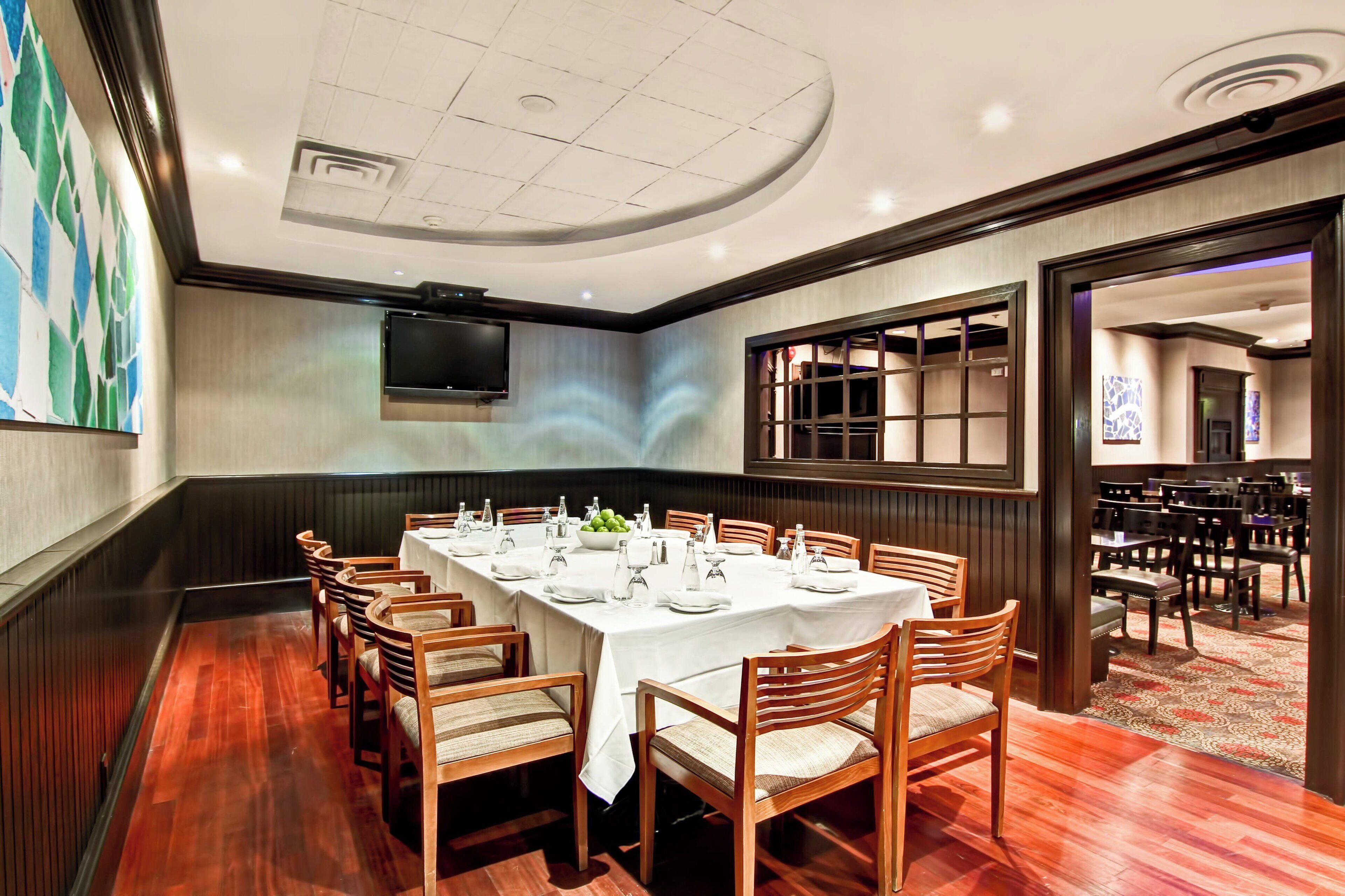 A conference room with a long table, chairs, and a television screen.