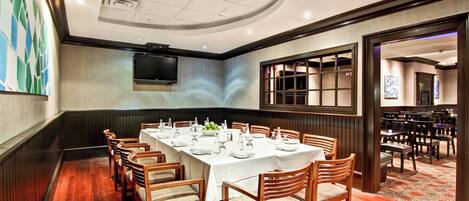 A conference room with a long table, chairs, and a television screen.