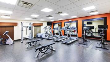 Un gimnasio con cintas de correr, elípticas y bancos de pesas.