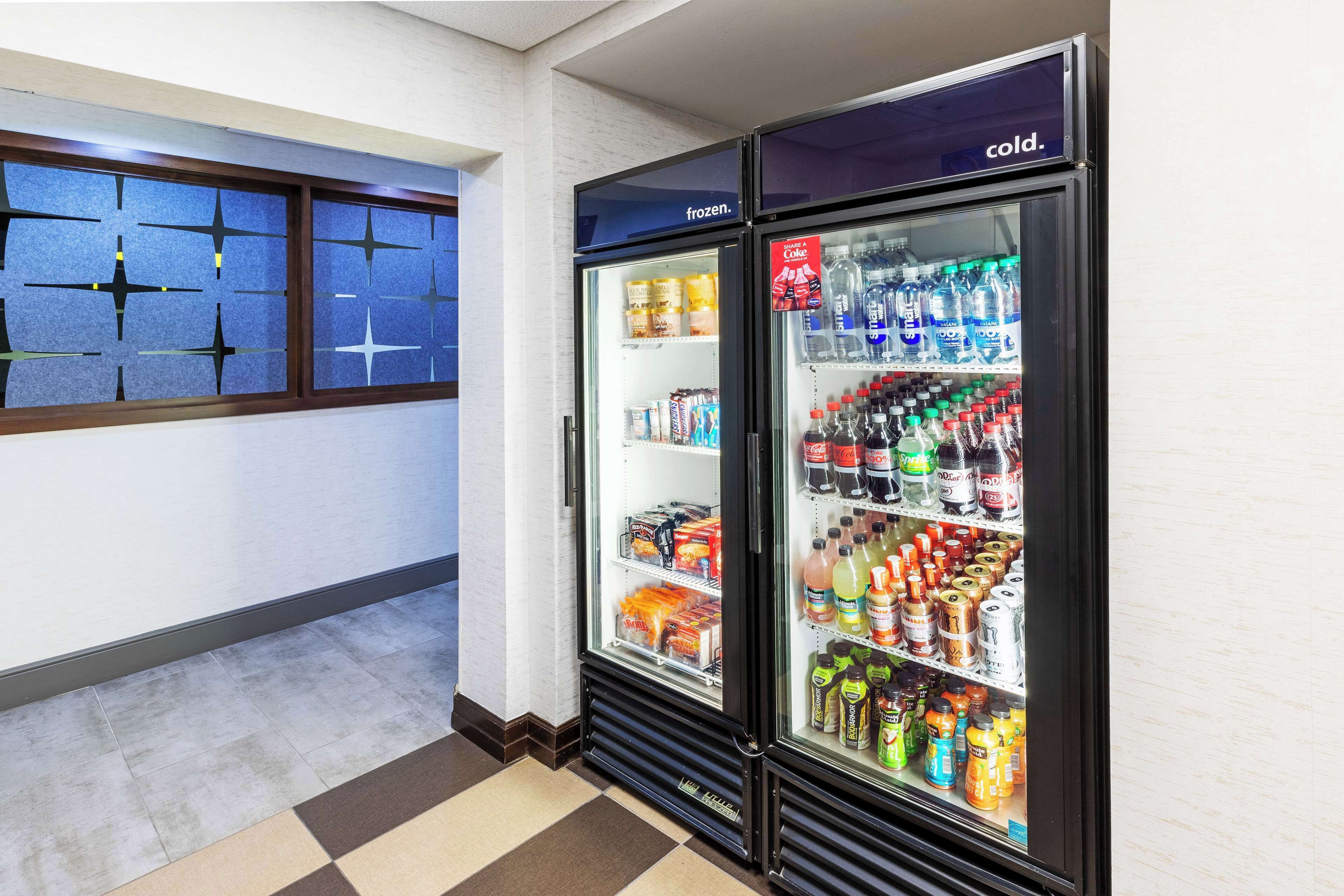 A corridor with two refrigerated beverage dispensers stocked with various drinks and snacks.