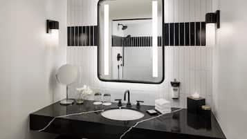 Une salle de bain moderne avec un lavabo en marbre noir, un miroir rond et un grand miroir rectangulaire placé au-dessus du lavabo.