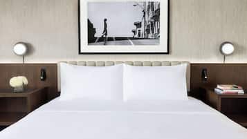 Ein Hotelzimmer mit einem Bett, zwei Nachttischen, einem gerahmten Bild an der Wand und einem Beistelltisch mit Büchern.