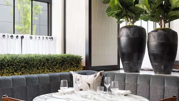 Un coin repas comprenant une table ronde, deux chaises, un canapé et une grande plante en pot.