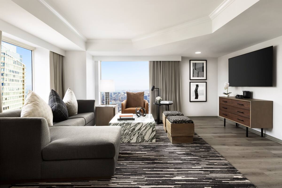 A modern living room with a sofa, armchairs, a coffee table, and a TV.