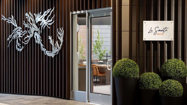 A modern building facade with vertical wooden slats, a glass entrance, and a sign reading "La Société Bar & Cafe". - Hyatt Regency San Francisco Downtown SOMA    (San Francisco)