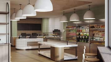 A modern cafe with a central island, bar seating, and a refrigerated display of beverages.
