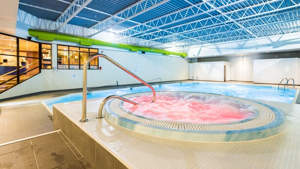 A hot tub with pink water, a green pipe, and a metal roof structure. - Holiday Inn Lancaster by IHG (Lancaster)