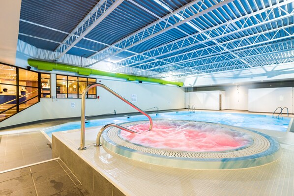 Un bain à remous avec de l’eau rose, un tuyau vert et une structure de toit en métal.