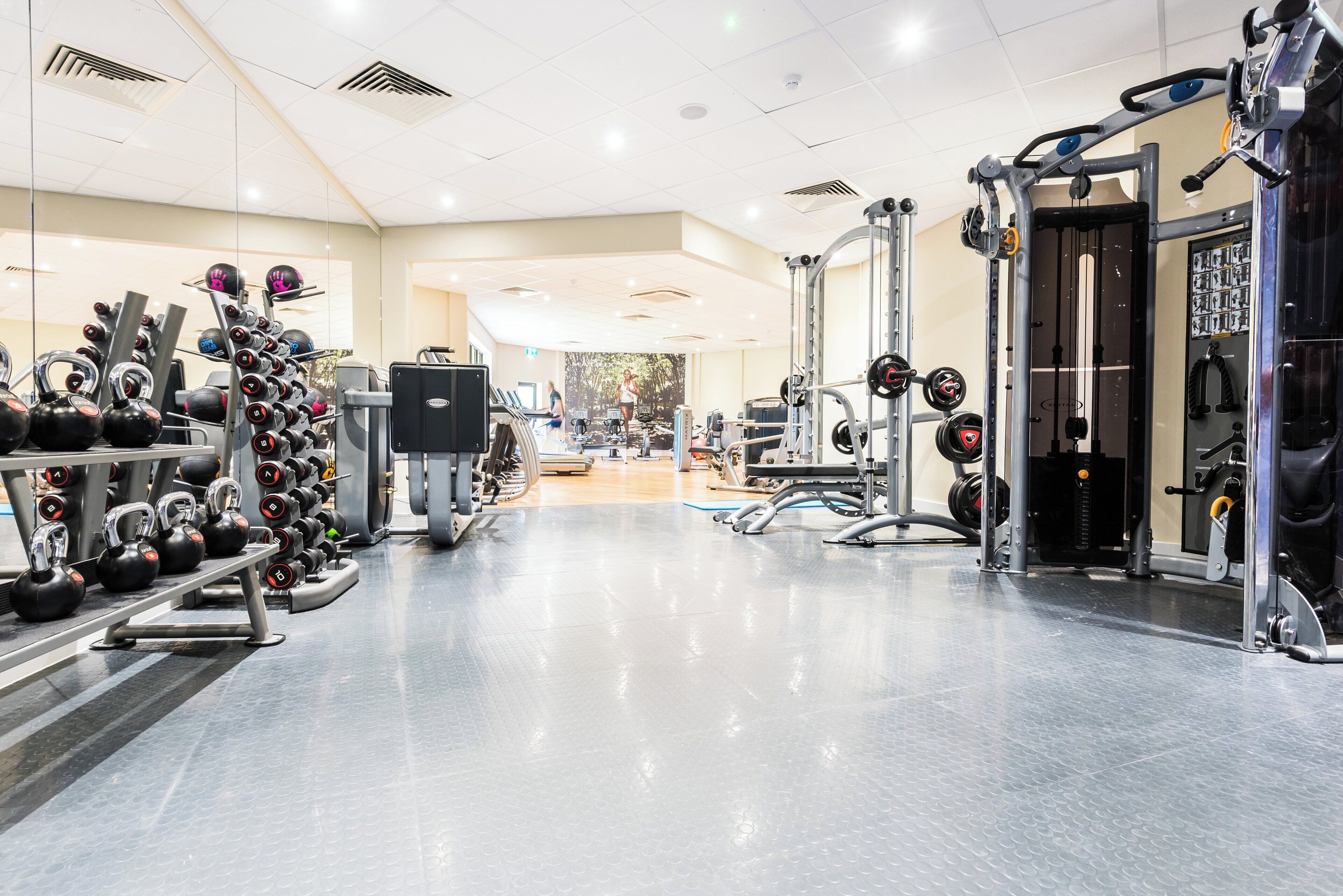 A gym with various exercise equipment, including kettlebells, dumbbells, and weight machines.