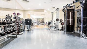 A gym with various exercise equipment, including kettlebells, dumbbells, and weight machines.