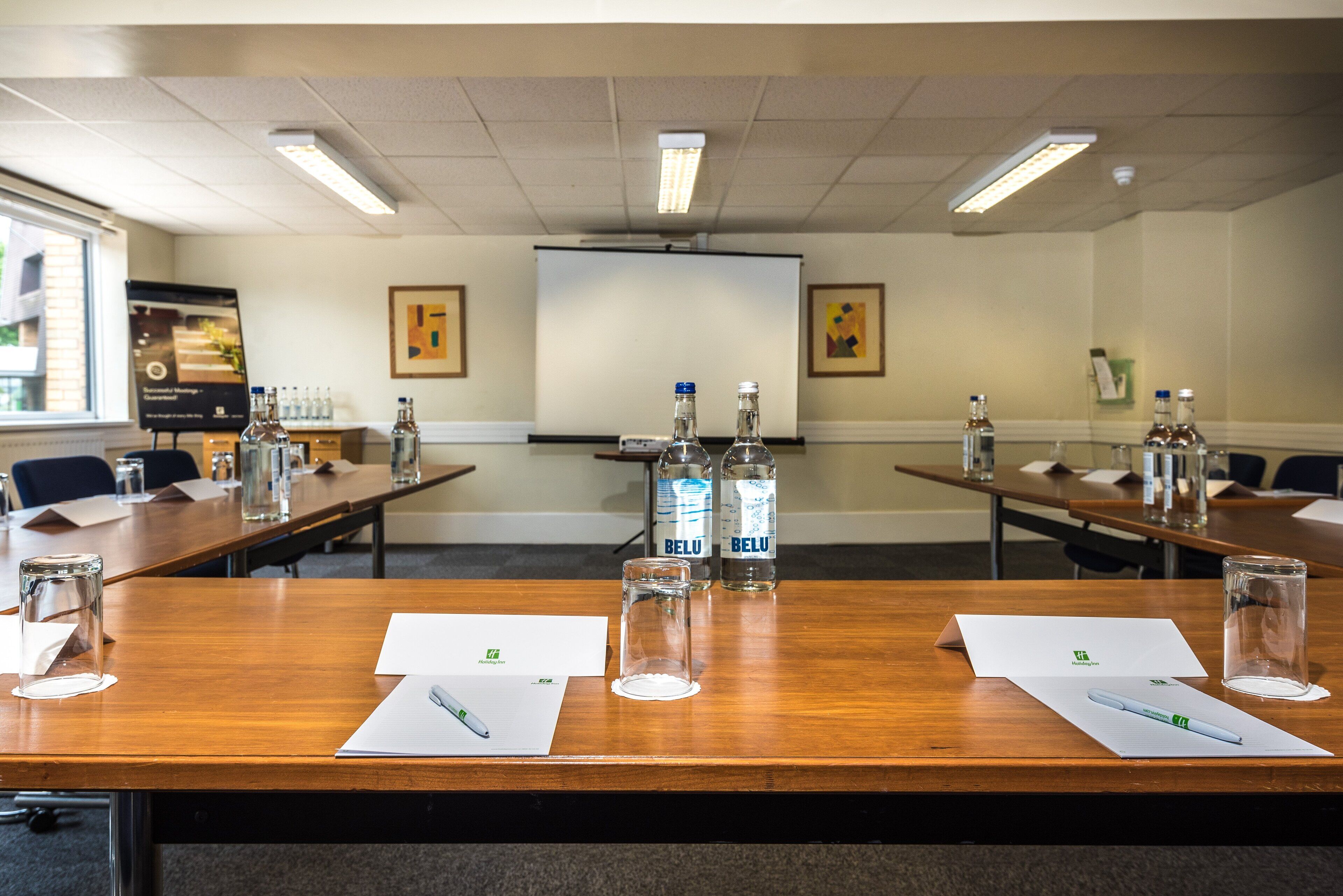 A conference room with wooden tables, water bottles, glasses, and papers.