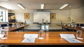 A conference room with wooden tables, water bottles, glasses, and papers.
