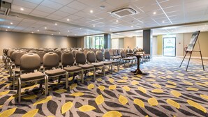 A conference room with rows of chairs, a carpet with a leaf pattern, and a whiteboard stand. - Holiday Inn Lancaster by IHG (Lancaster)